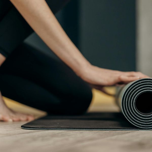 Person rolling out a yoga mat in a bright room.